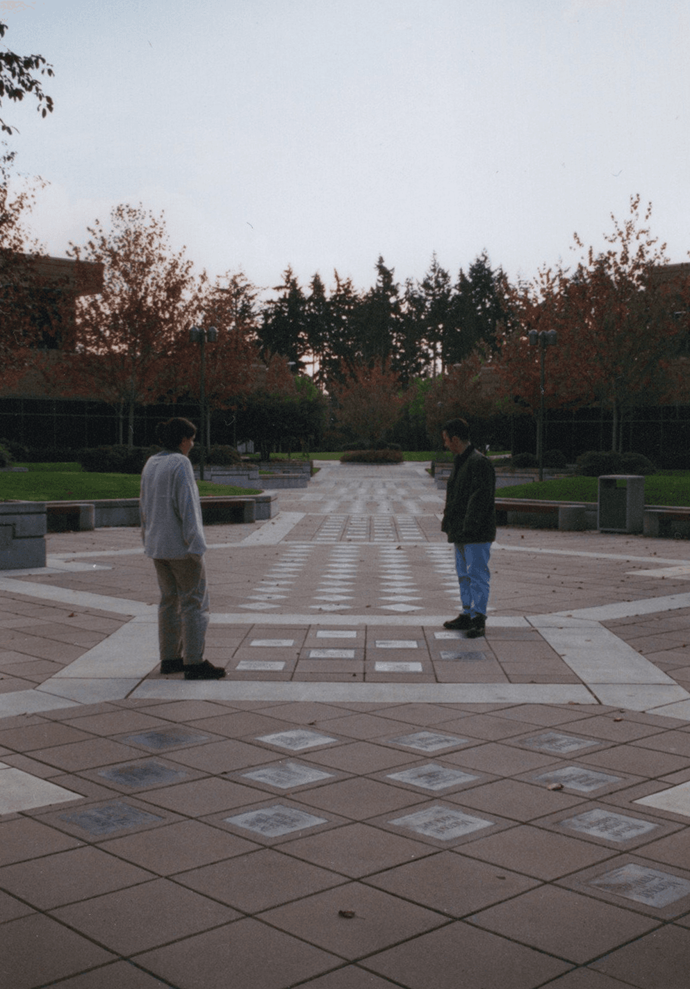 Two people standing among brass Microsoft product plaques set into a courtyard